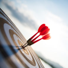 Business goal success concept shown by red darts hitting the bulls eye