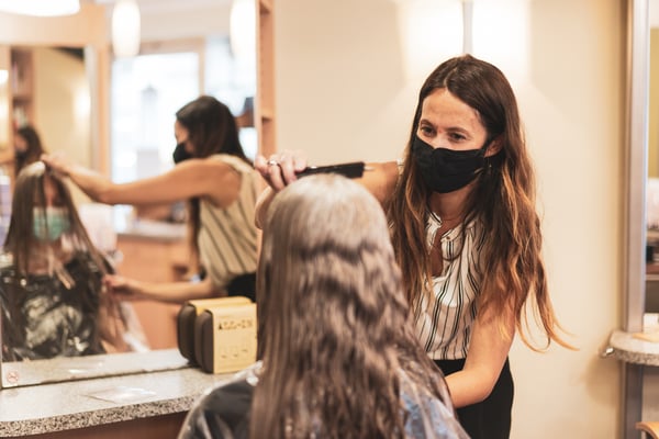 hairdresser with mask enjoying to work again in her hair salon after lockdown is over