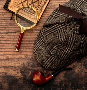 sherlock holmes detective hat, smoking pipe, retro magnifying glass and old book isolated on wood table top with copy space