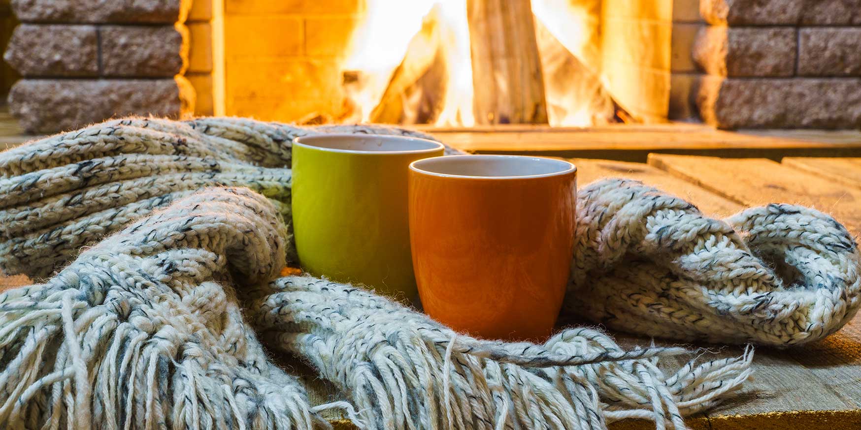 Mugs for tea or coffee, wool things near cozy fireplace