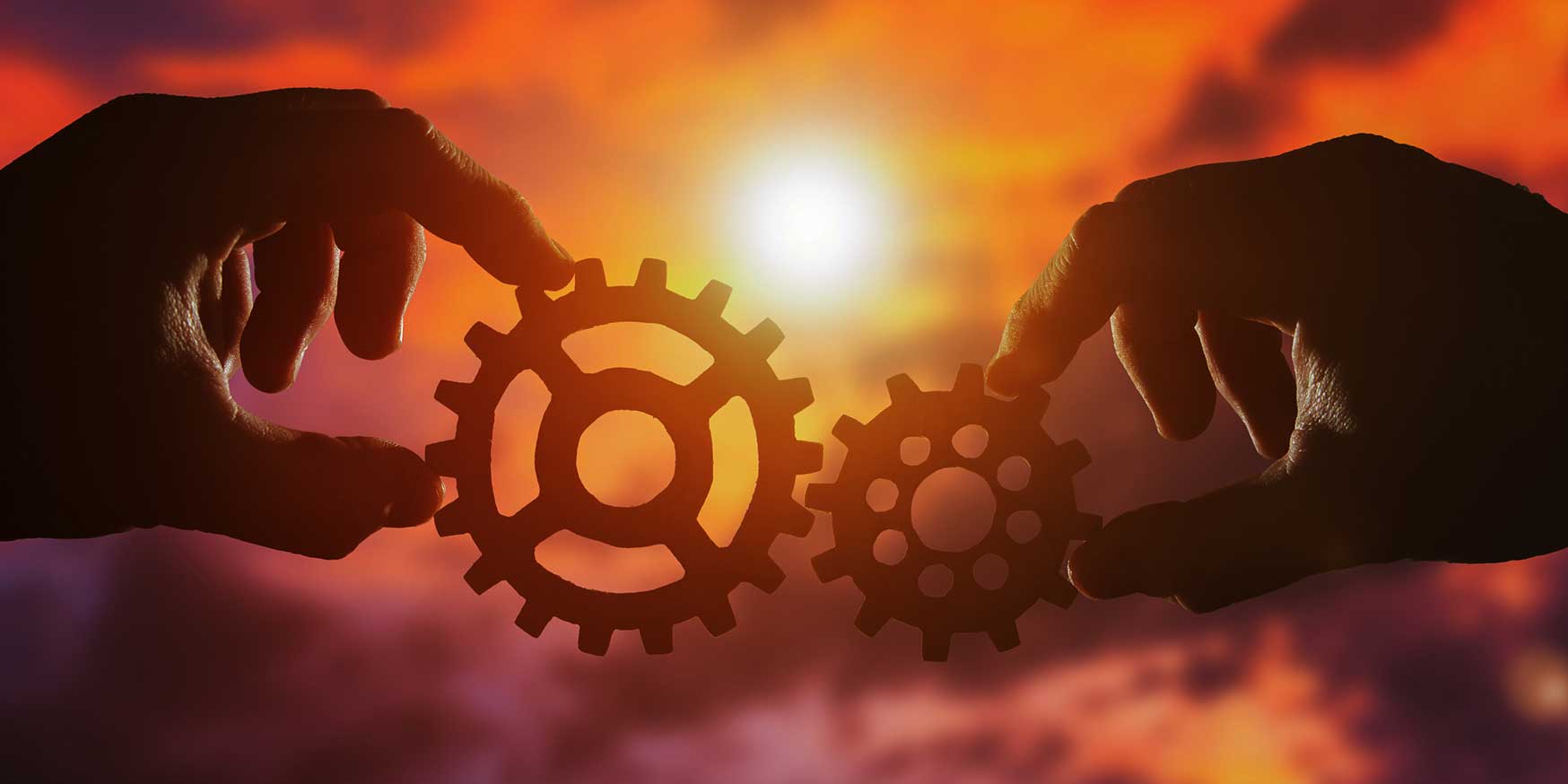 Two gears fit together with a dawn background, representing building a team with the best fit from the start