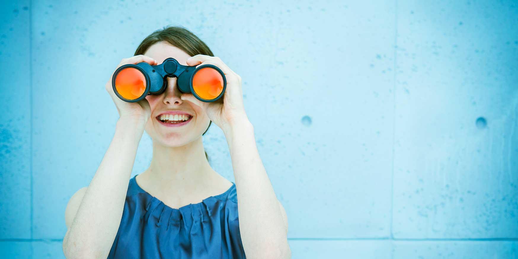 Businesswoman holding binoculars looking ahead