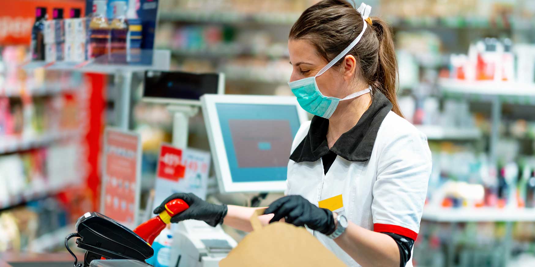 Cashier in mask and gloves working at the register