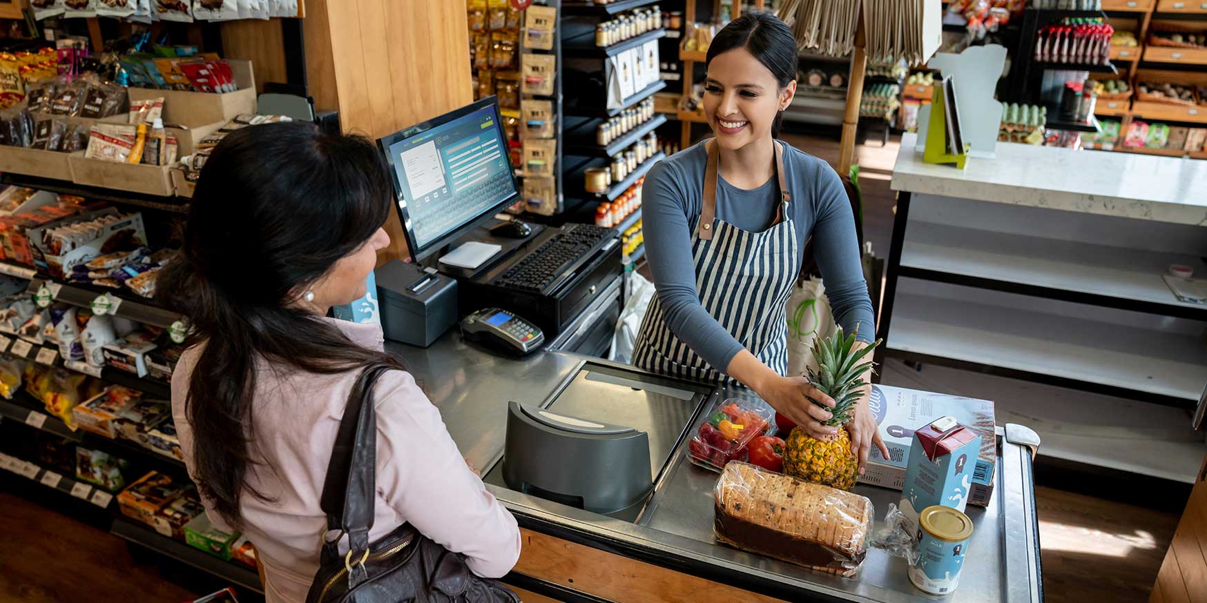 Supermarket worker happily helping a customer at register