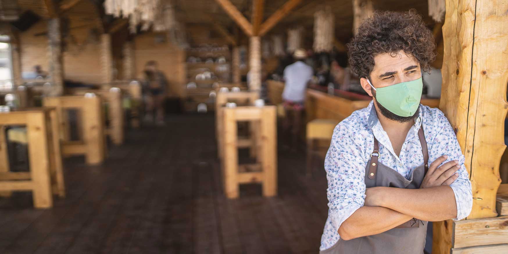 Dissatisfied, masked hourly worker at a restaurant, wishing they were off.